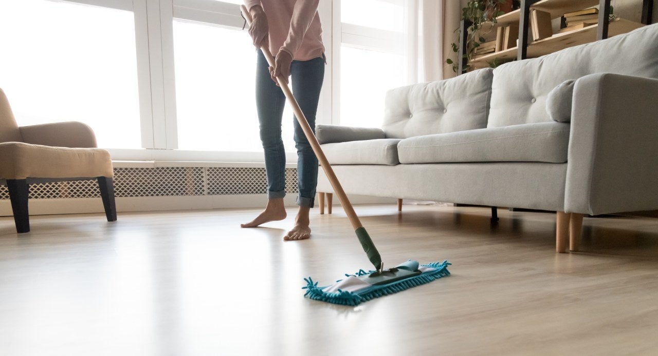 Mulher passando limpador perfumado na sala com um mop para deixar o ambiente mais fresco e cheiroso 