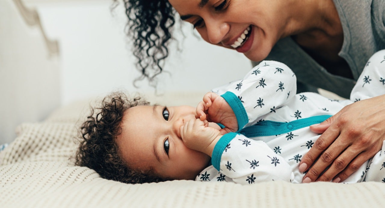 Mamãe se divertindo com seu pequeno antes de dormir, depois de vestir um pijama para bebê confortável