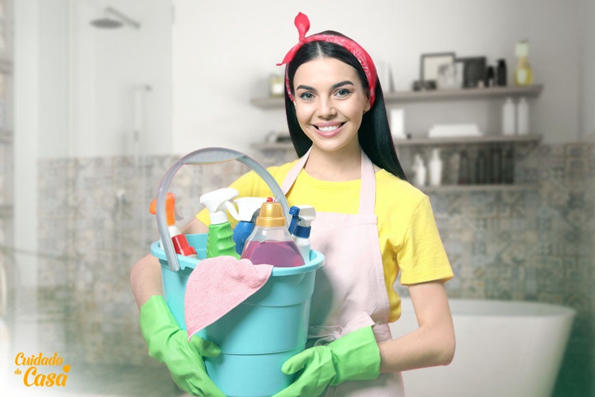 Mulher na lavanderia pronta para arrumar casa com um balde na mão mostrando os principais produtos para lavar banheiro