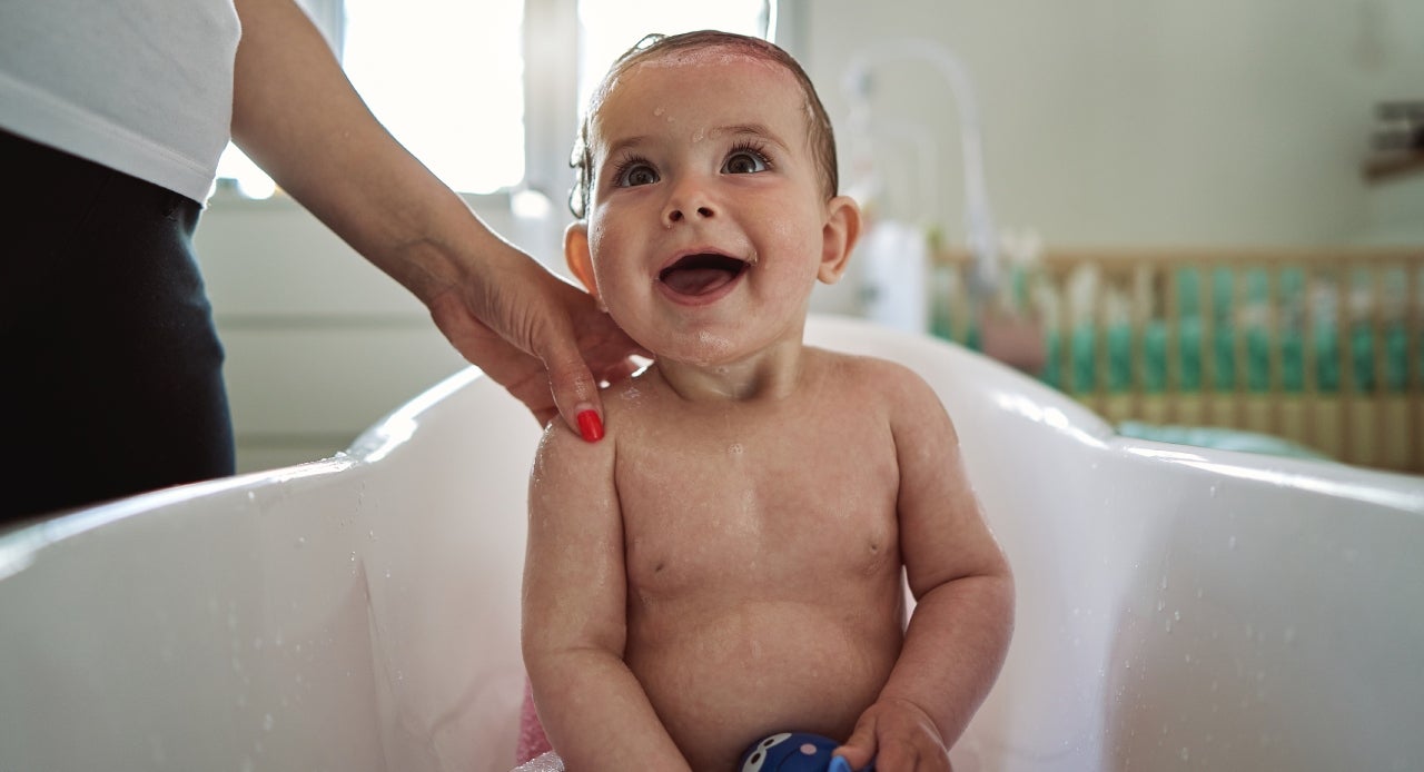 Mulher dando banho na banheirinha e observando com cuidado os sinais de alergia no bebê