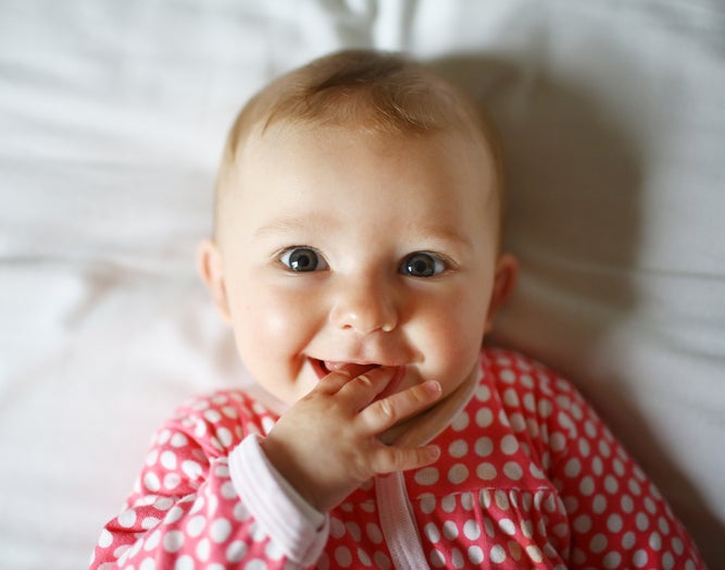 Um pequeno sorridente usando um pijama para bebê divertido, vermelho com bolinhas brancas
